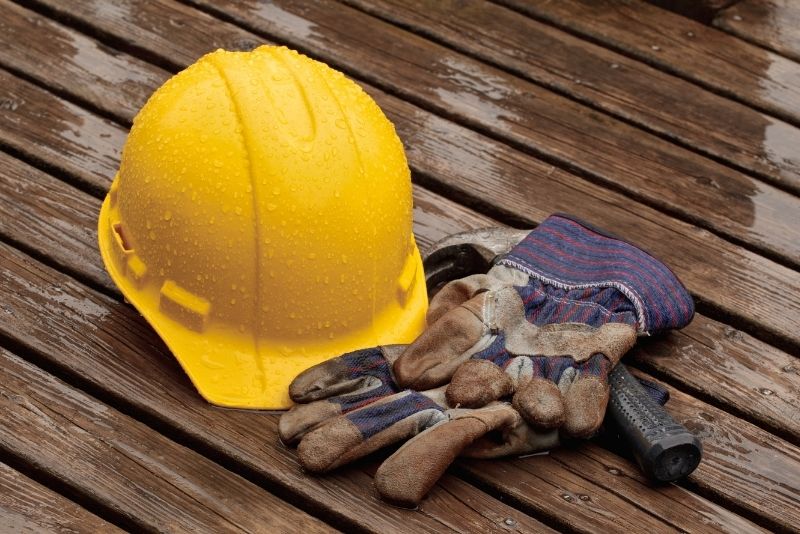 yellow coloured construction and a pair of gloves on a wooden floor